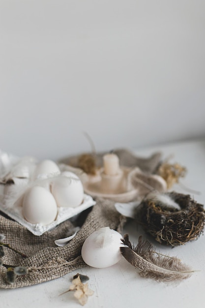 Bodegón rústico de Pascua Huevos de Pascua naturales en bandeja plumas ramas de sauce anidan en la mesa