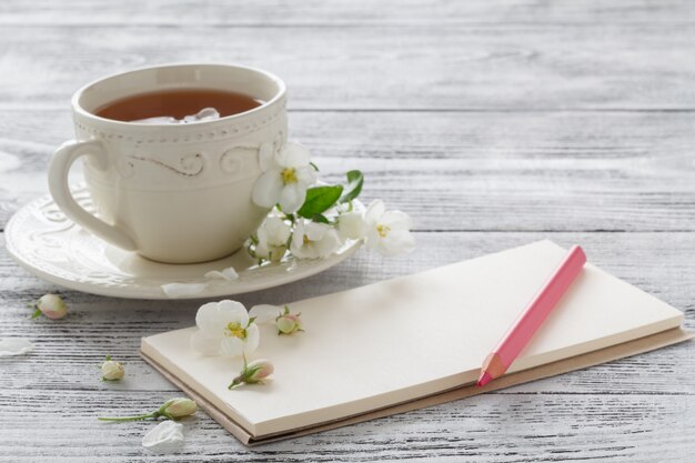 Bodegón con taza de té y rama de flor