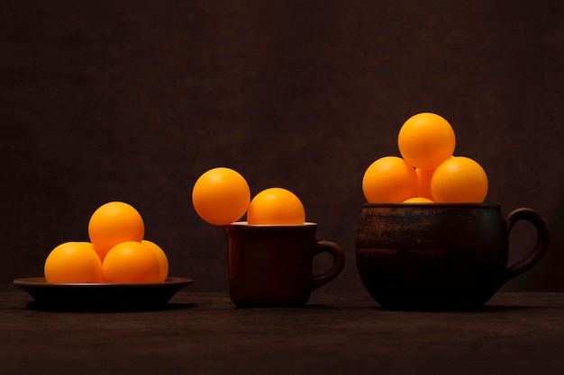 Bodegón con tazas marrones y bolas naranjas