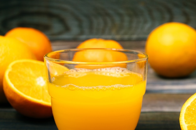 Bodegón vaso de jugo de naranja fresco en mesa de madera