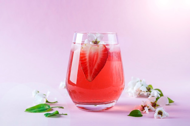 Bodegón con vaso de refrescante sangría de fresa con vino espumoso, fresa, cubitos de hielo