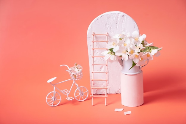 Bodegón de verano con flores en una bicicleta decorativa de escalera de pedestal y arco sobre un fondo rosa