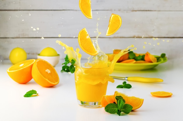 Bodegón de verano con splash de jugo de naranja y menta en blanco. Estilo de vida saludable .