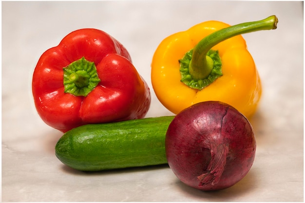 Bodegón con verduras frescas maduras: pimentón rojo y amarillo, cebolla morada y pepino verde