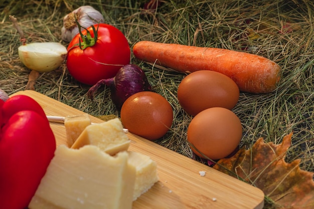 bodegón con verduras y queso en una tabla para cortar en el heno