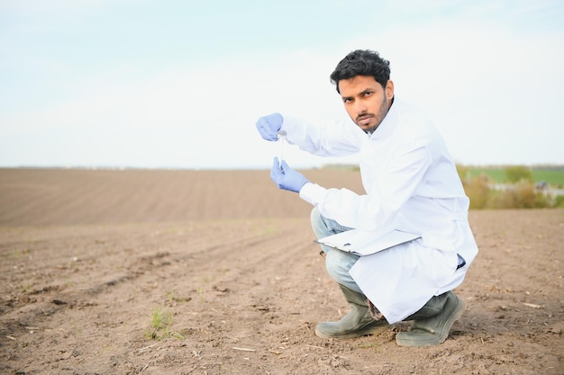 Bodentests Indischer Agronomiespezialist entnimmt Bodenproben zur Fruchtbarkeitsanalyse Hände in Handschuhen in Großaufnahme Umweltschutz Bio-Bodenzertifizierung Feldforschung