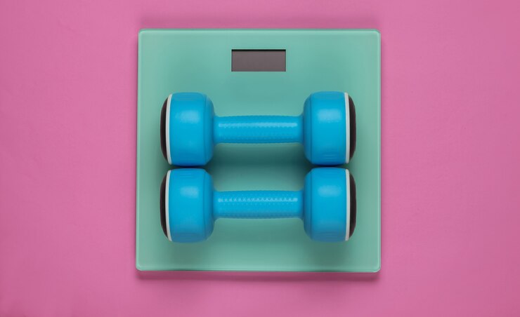 Foto bodenwaage und hantel auf rosa hintergrund. sportkonzept, fitnesstraining. studioaufnahme. ansicht von oben