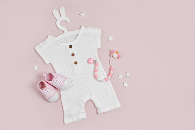 Body blanco en una linda percha con orejas de conejo y zapatos de bebé y juguetes. Conjunto de ropa de bebe