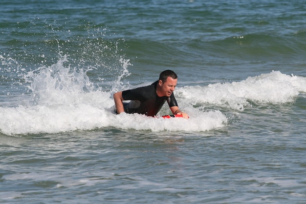 Body boarder montando una ola en el mar por diversión