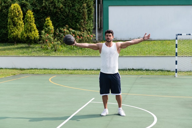 Bodybuilder, der draußen Basketball spielt