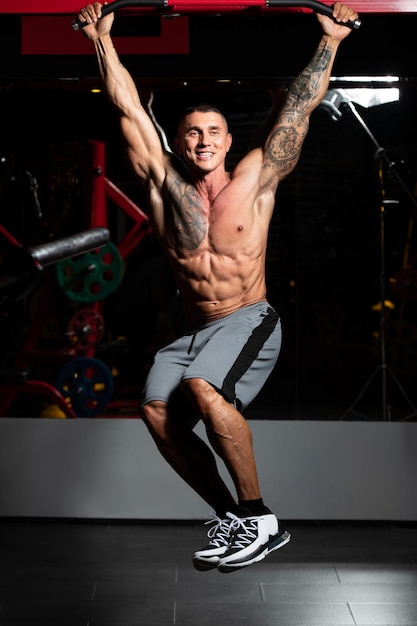 Bodybuilder, der hängende Beinübungen durchführt, hebt eine der effektivsten Bauchmuskelübungen