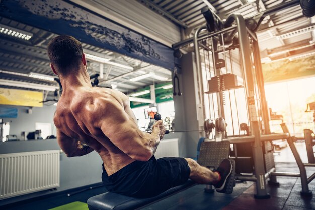 Bodybuilder forte que faz o exercício pesado para trás na máquina