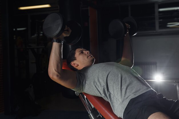 Foto bodybuilder-training im fitnessstudio: brust-kurzhantel-bankdrücken.