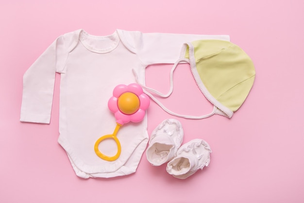 Bodysuit verde chocalho e botas brancas para um recém-nascido em um fundo rosa