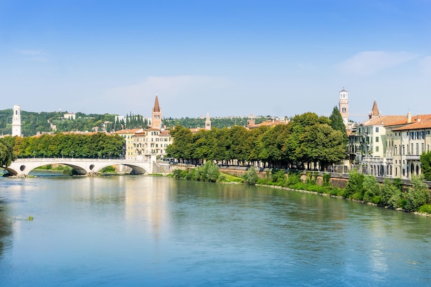 Bogenbrücke über den Fluss durch Bäume in der Stadt gegen den blauen Himmel