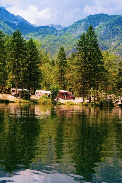 Bohinj, Eslovenia - 3 de junio de 2019: Paisaje con camping de remolques de caravanas RV en el lago Bohinj, Eslovenia. Naturaleza y autocaravanas camper en Slovenija. Vista de la furgoneta de la casa rodante y las montañas verdes de los Alpes alpinos