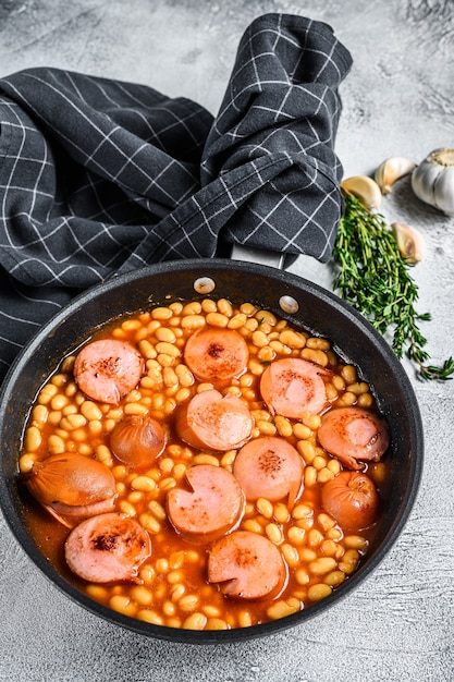 Bohnen mit Würstchen in Tomatensauce in einer Pfanne