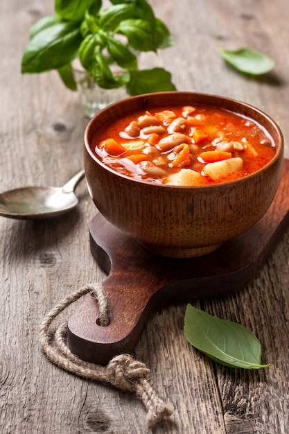 Bohnensuppe in einer hölzernen Schüssel auf dem alten hölzernen Hintergrund