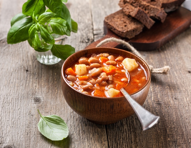 Foto bohnensuppe in einer hölzernen schüssel auf dem alten hölzernen hintergrund