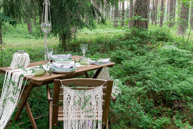 Boho estilo recepção de casamento mesa de jantar com toalha de mesa de macramê, decoração em uma mesa de madeira rústica