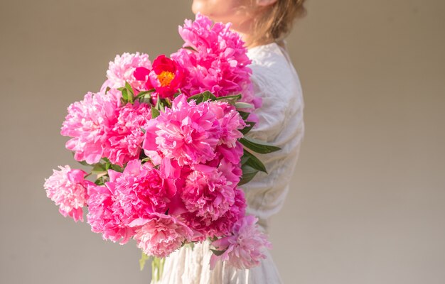 Boho-Mädchen, das rosa Pfingstrosen im Strohkorb hält.