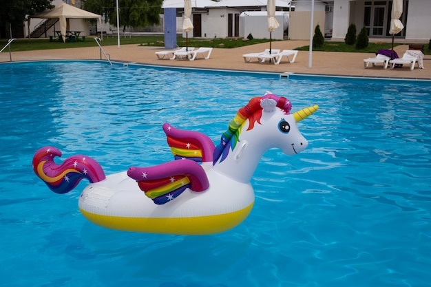 Bóia de piscina Unicorn em fundo de água azul, tubo inflável de natação