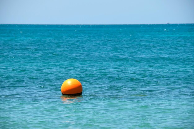 Boia laranja flutuando nas ondas da superfície do mar. Conceito de segurança de vida humana.