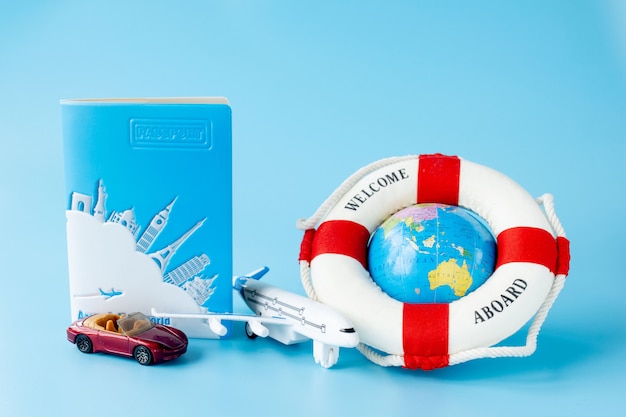 Boia salva-vidas, globo, modelo de avião e carro na superfície azul