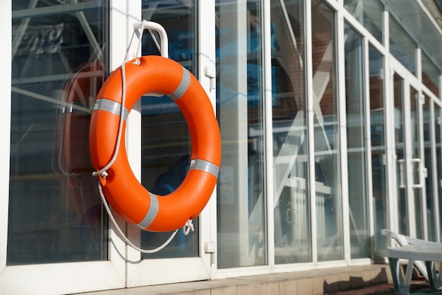 Bóia salva-vidas laranja na parede de proteção da piscina