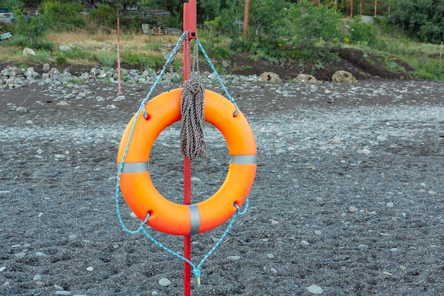 Bóia salva-vidas laranja na praia à beira-mar..