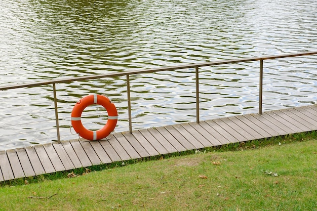 Boia salva-vidas laranja perto da lagoa. Salvando e preservando a vida humana. Segurança na água. P de alta qualidade