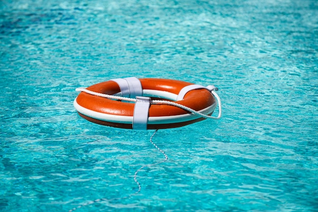 Boia salva-vidas no anel da piscina azul Boia salva-vidas flutua na água azul