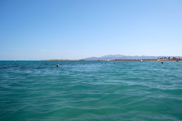 Boias amarelas flutuando na superfície do mar como marcador para restrição de natação em águas profundas em resort tropical com vista da linha costeira à distância. Conceito de segurança da vida humana.