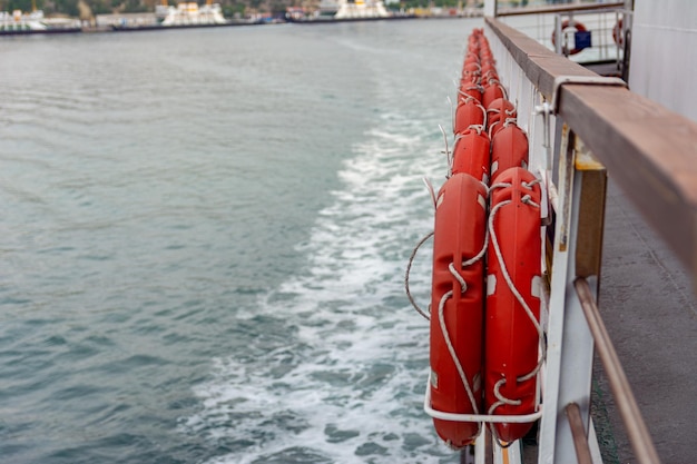 Boias salva-vidas penduradas a bordo de uma balsa marítima flutuando nas ondas