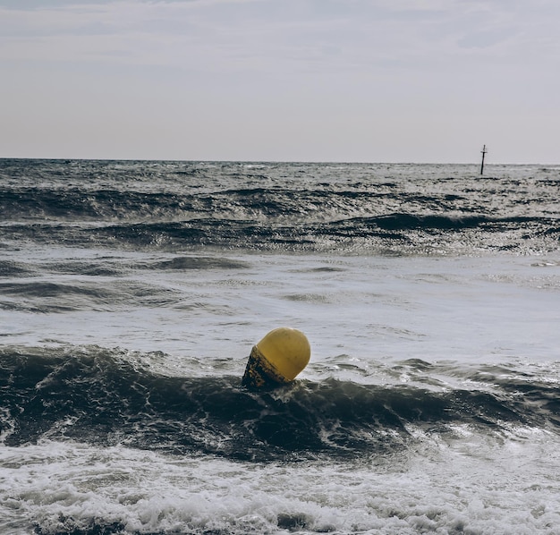 Boje in den Meereswellen mit Schaum Leerer Strand Sommerferien reisen Stürmischer Ozean