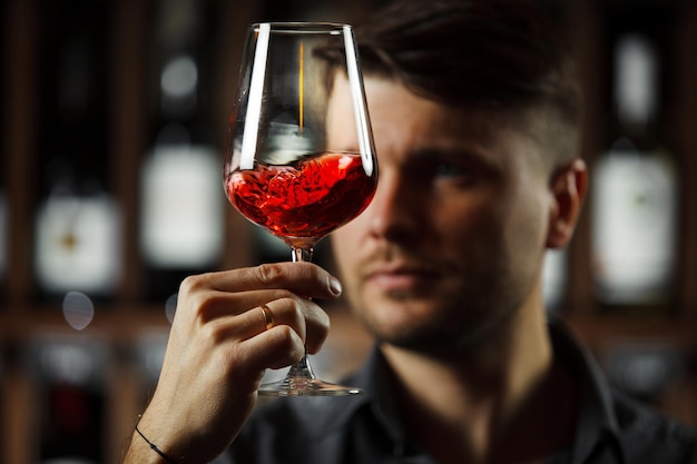 Bokal de vino tinto en el fondo sumiller masculino apreciando la bebida