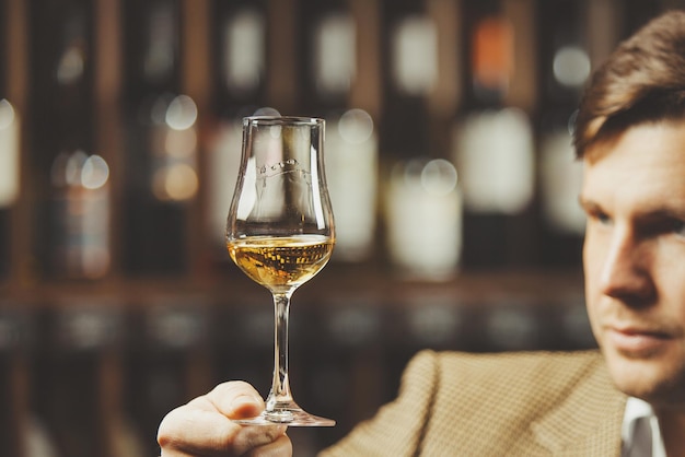 Bokal Whisky auf Hintergrund männlicher Sommelier schätzt Getränk