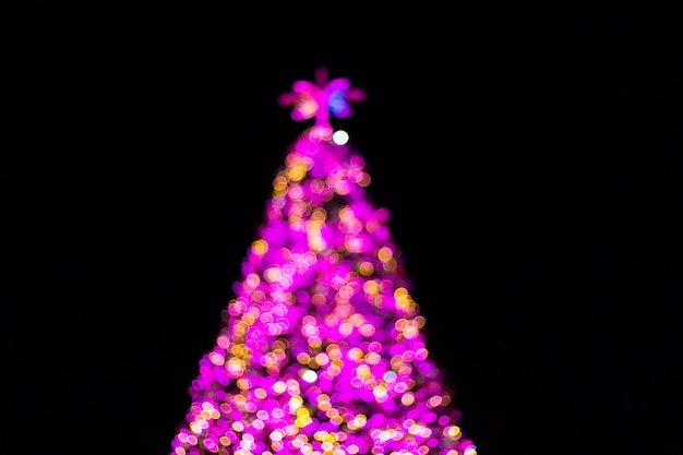 Bokeh abstrato claro colorido da árvore de natal e do fundo do ano novo feliz.