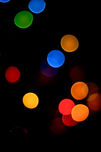 Bokeh azul verde amarillo rojo tonos sobre fondo negro en la víspera de Año Nuevo