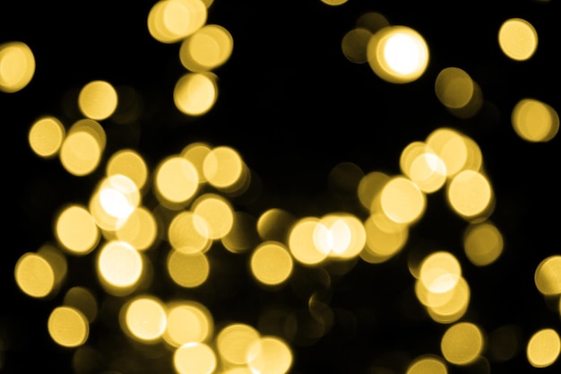 Bokeh desfocado, grandes luzes douradas de natal em fundo preto Textura abstrata de brilho dourado desfocado