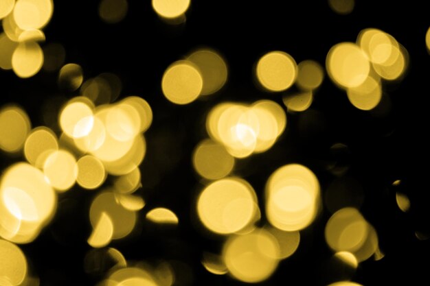 Bokeh desfocado, grandes luzes douradas de natal em fundo preto, textura abstrata de brilho dourado