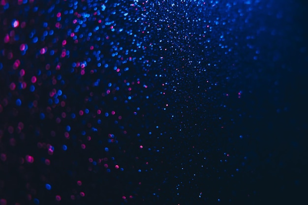 Foto bokeh-funken neon-glitter-hintergrund festliche glühreflexion defokussiertes blau-rosa farblicht schimmerndes kreismuster auf dunkelschwarzer abstrakter überlagerung