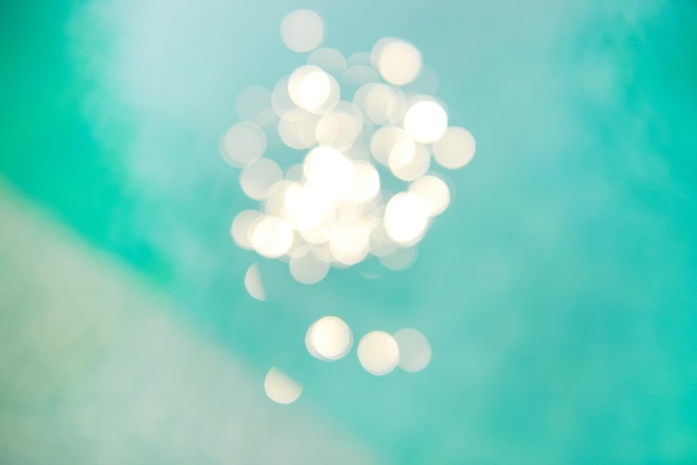 Bokeh-Lichteffekte mit weichem Fokus über einem gewellten, blauen Wasserhintergrund im Pool.