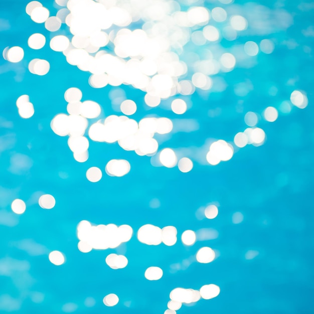 Bokeh-Lichteffekte mit weichem Fokus über einem gewellten blauen Wasserhintergrund im Pool