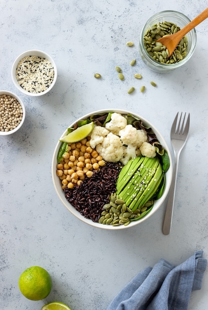 Bol con aguacate, arroz negro, garbanzos, repollo, espinacas y ensalada. Alimentación saludable. Comida vegetariana.