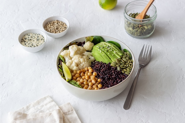 Bol con aguacate, arroz negro, garbanzos, repollo, espinacas y ensalada. Alimentación saludable. Comida vegetariana.