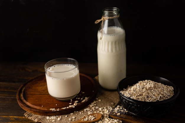 Un bol con avena junto a una botella de leche y un vaso. Vista cortada.