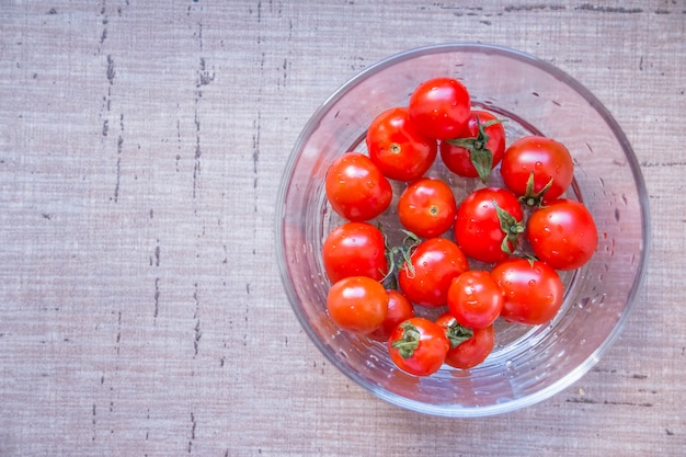 Bol de cristal transparente con pequeños tomates cherry. Vista superior de comida saludable