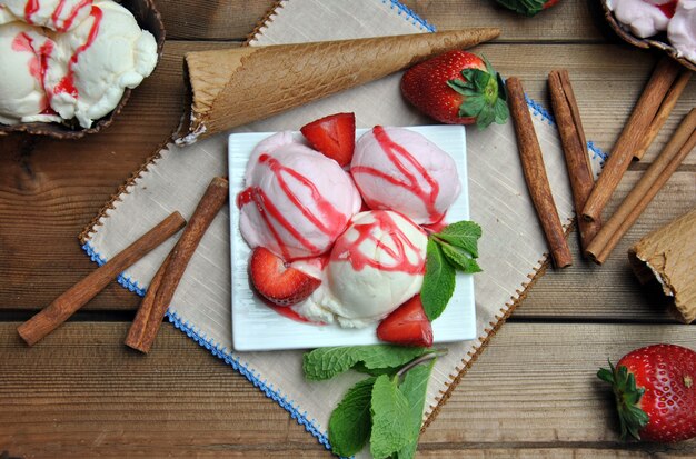 Bol de helado con vainilla y sirope de fresa, acompañado de fresas.