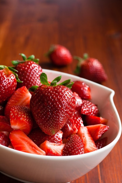 Un bol lleno de fresas frescas cortadas en trozos y listas para comer